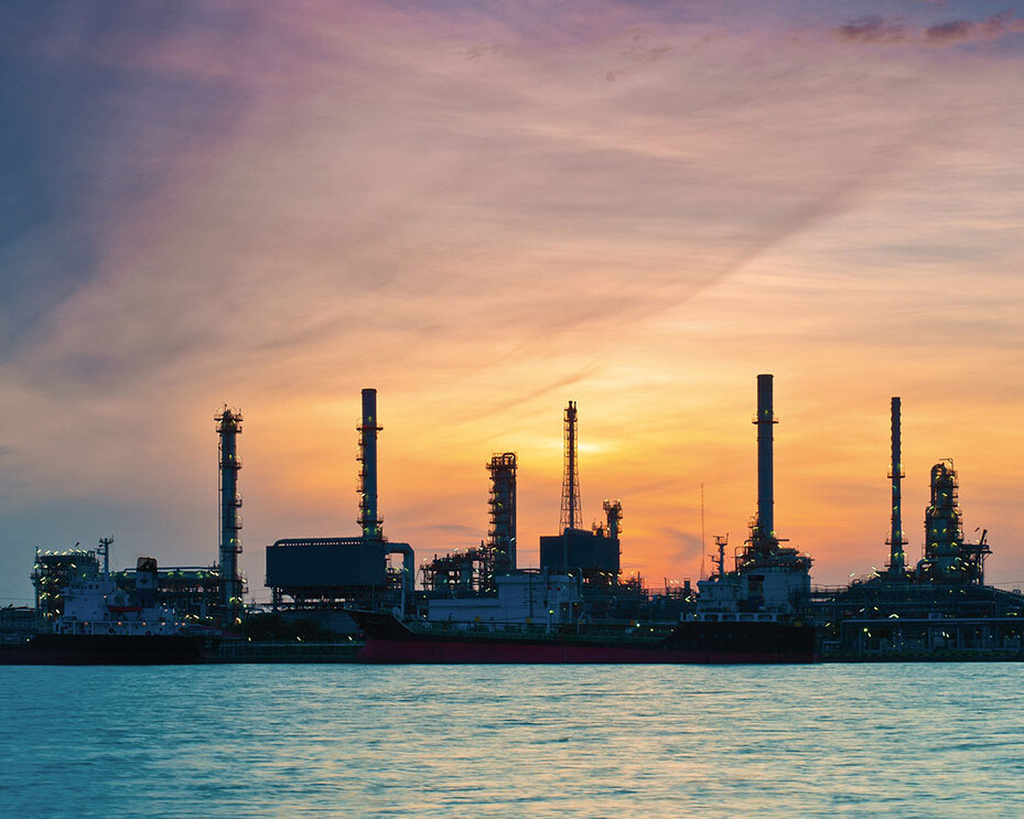 Refinery with sea in foreground and sunrise in background